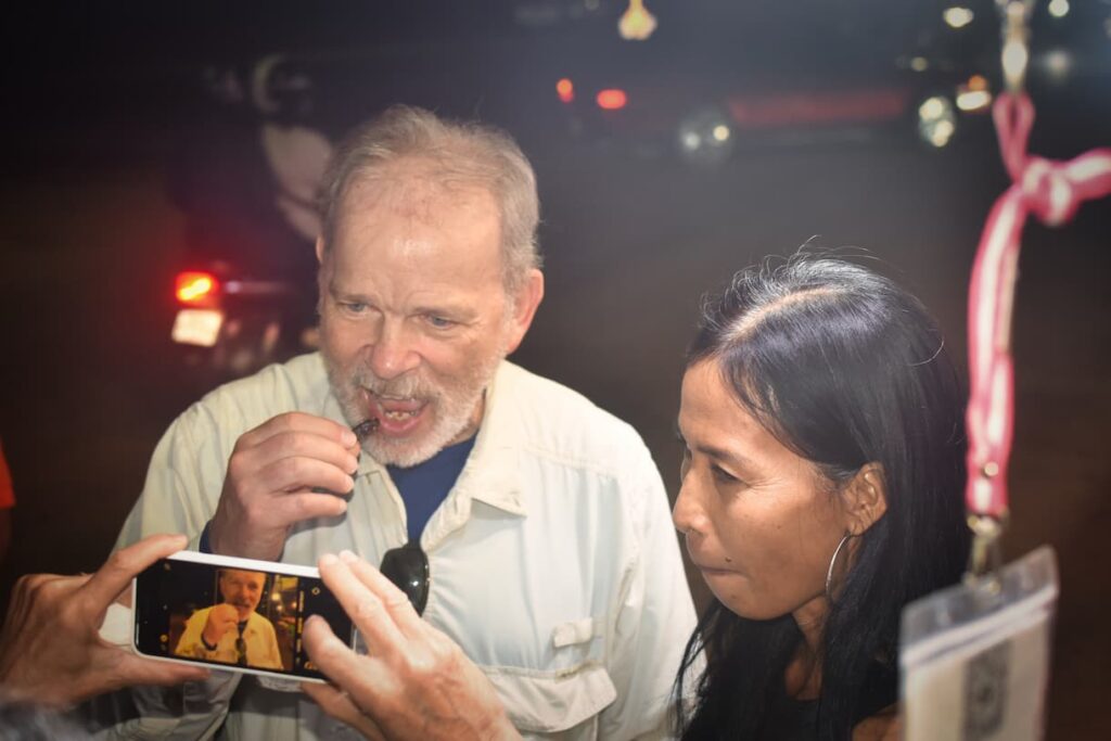 A guest tasting a night market snack while the vendor looks on