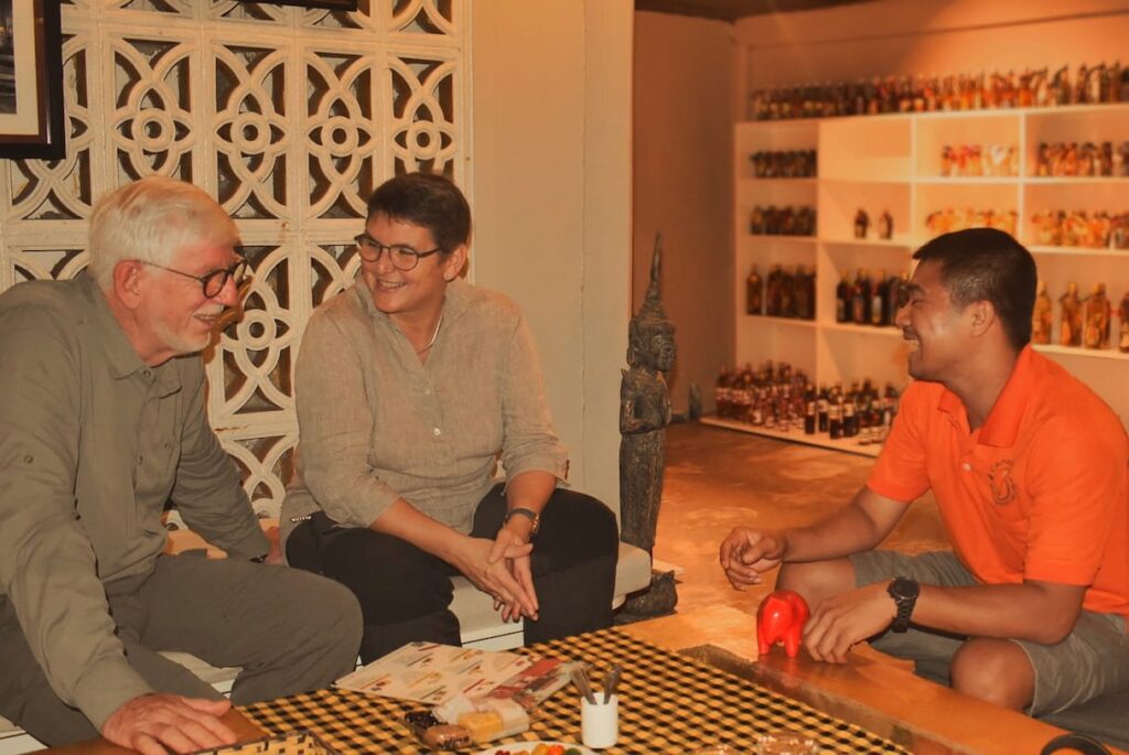 Guests talking with their guide in the tasting room, shelves of small bottles behind them